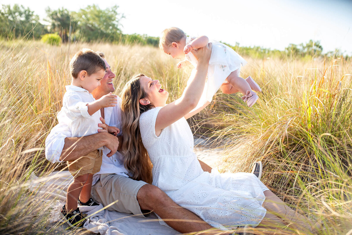 Family playing in the tall grass at sunset 