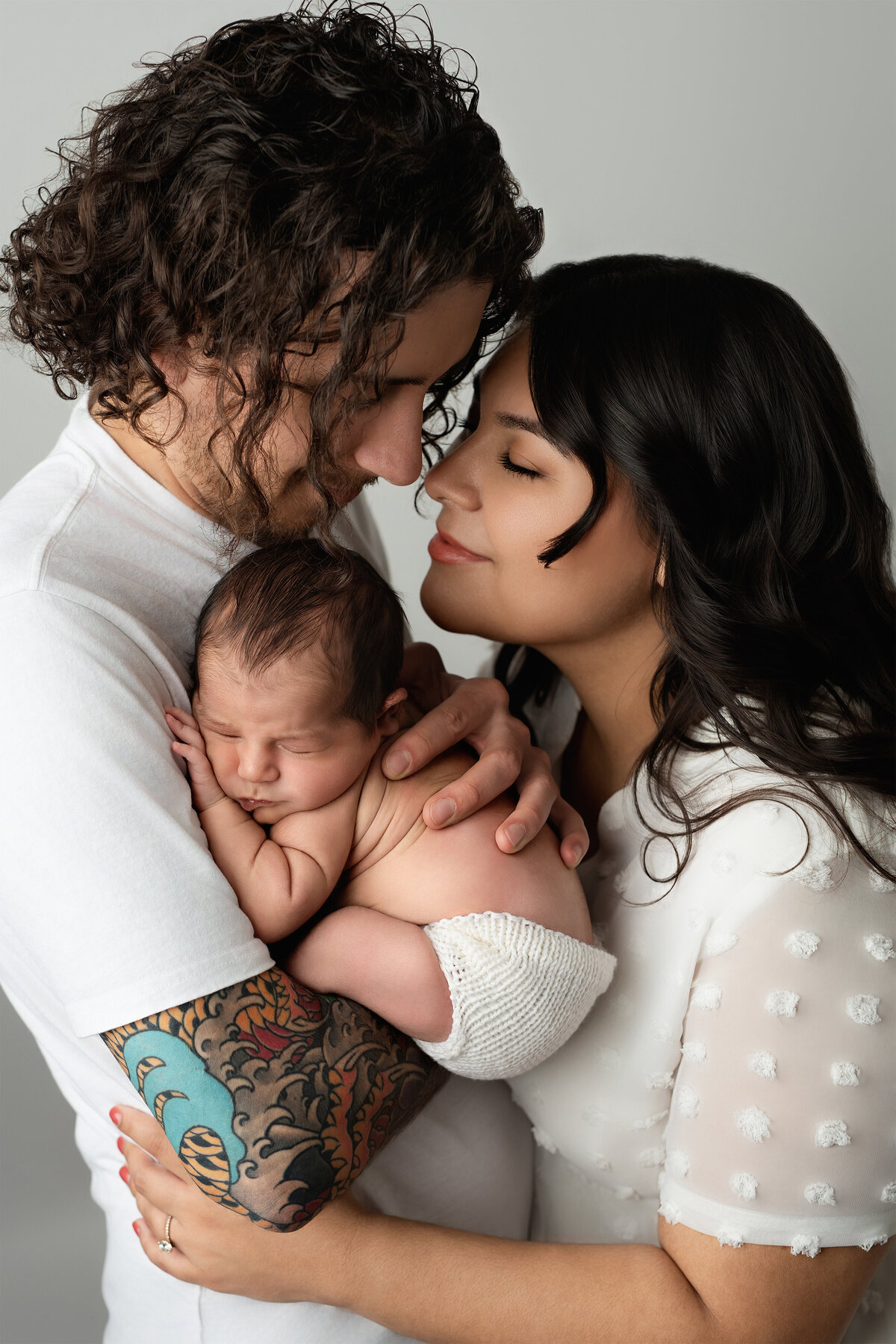 Emotional family studio portrait with parents embracing their newborn baby | Paris Ontario