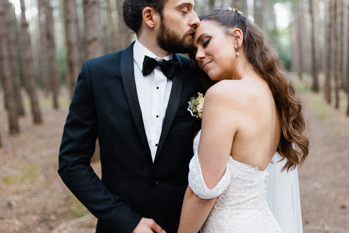 Deux mariées élégants se font une étreinte dans une forêt de pin lors de leur mariage.