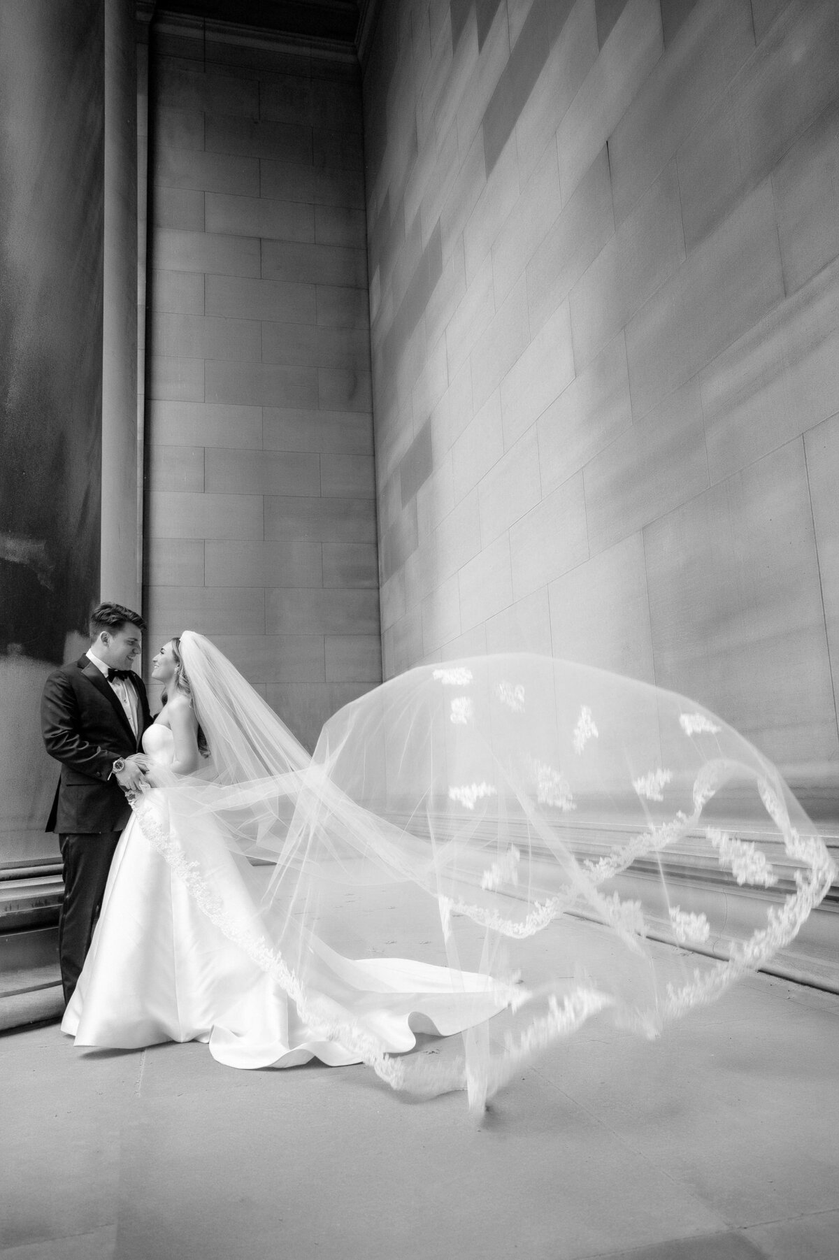 bride and groom kissing at mellon institute columns as the veil blows in the wind