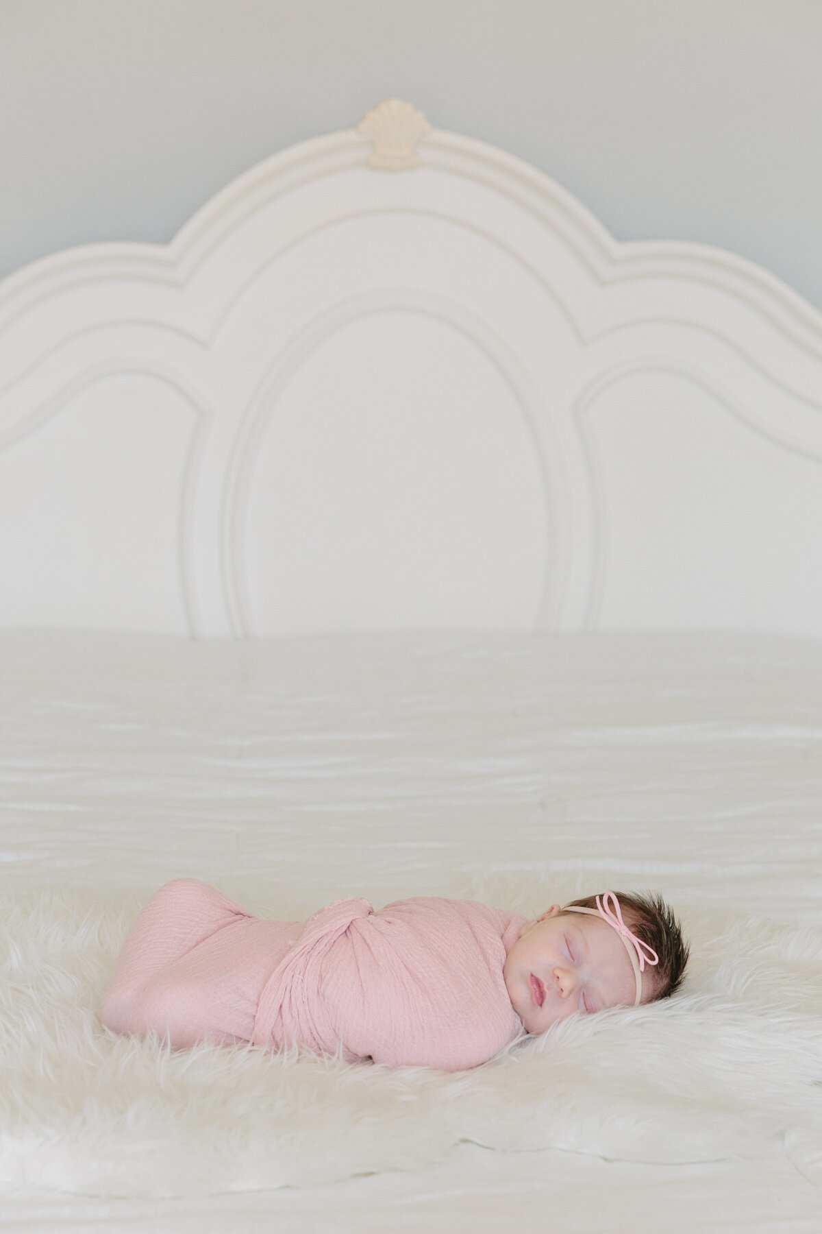 A newborn baby swaddled on a bed sleeping
