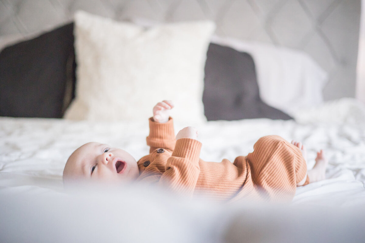 baby boy laying on a white bed