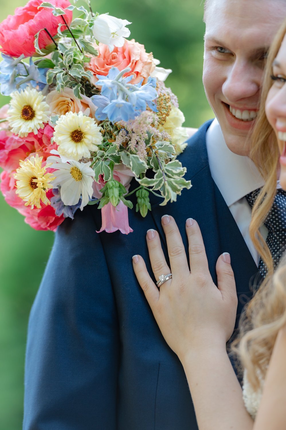 close up photo of bride ring and bouquet hugging groom and laughing