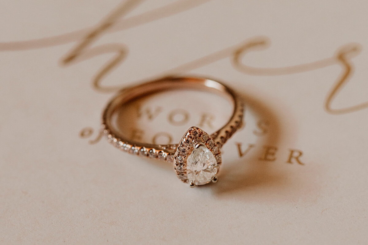 rose gold engagement ring sitting on brides vow book