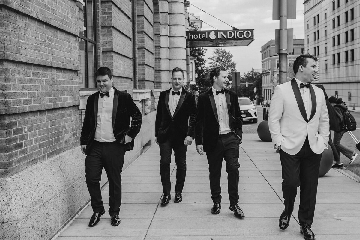 A group of friends in suits walking on a sidewalk 