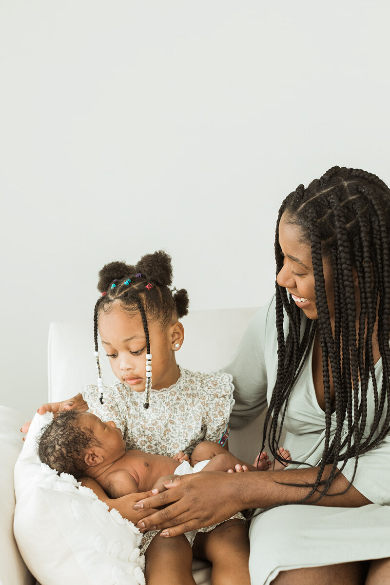 mom helps big sister hold her new baby brother