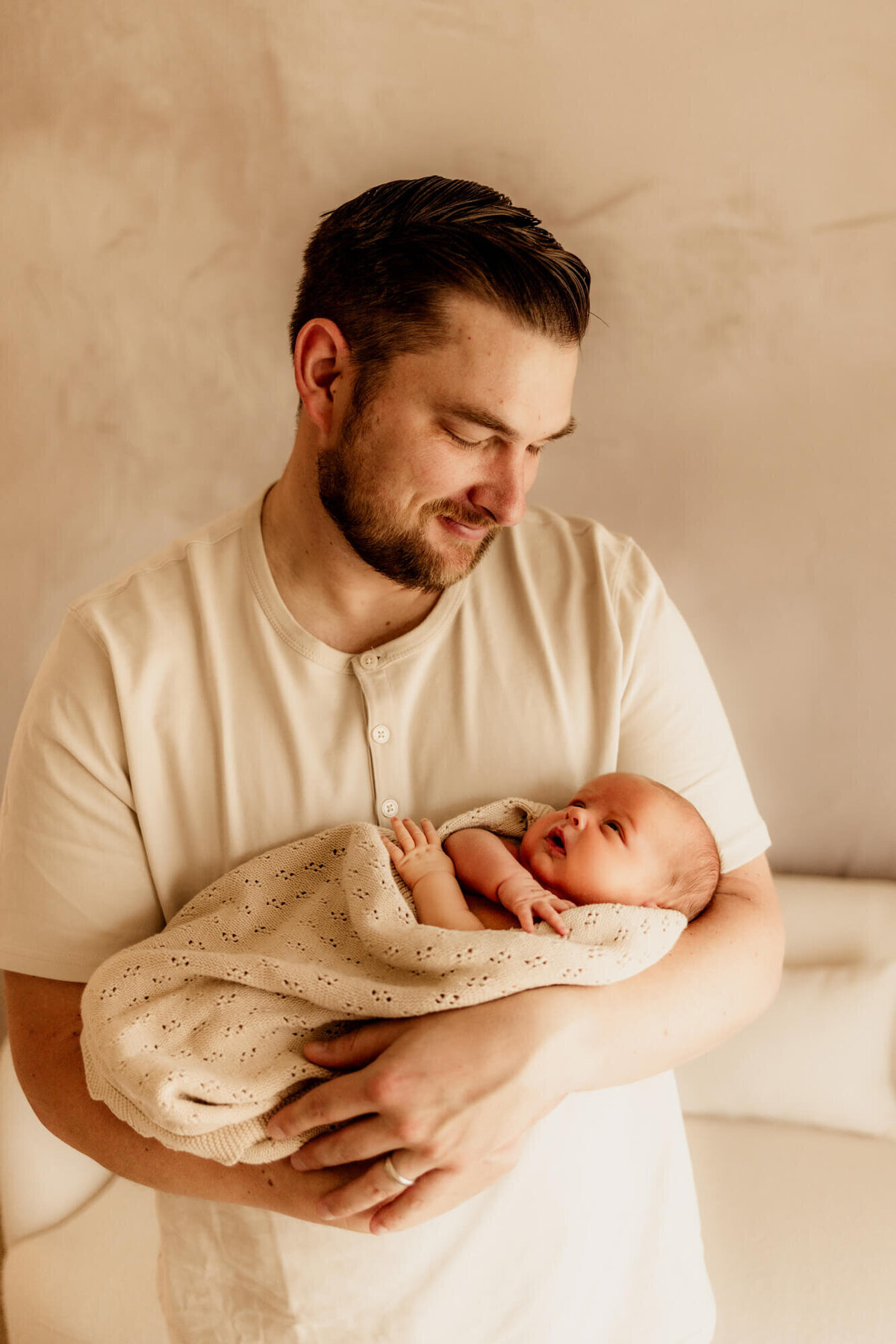 Baby boy looks up at his father while he smiles down at him.