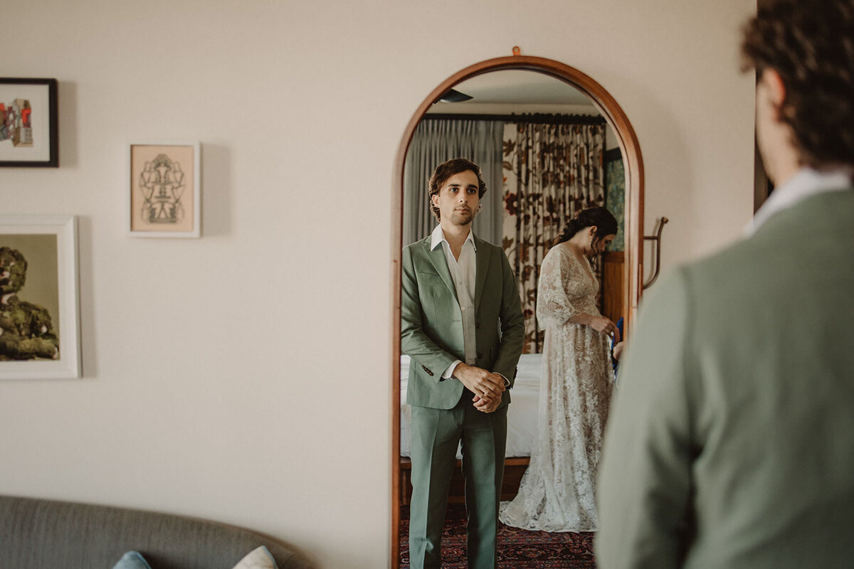 A person looking in the mirror and adjusting their suit 