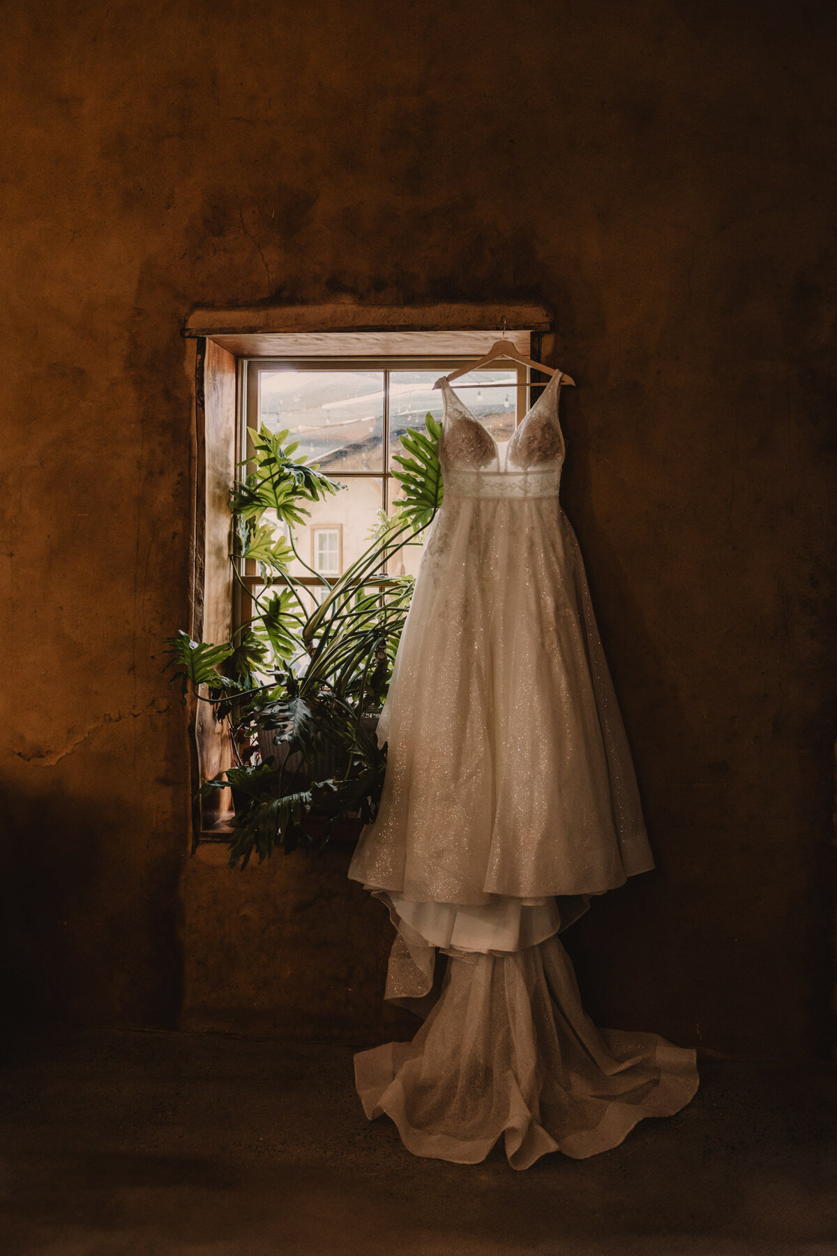 A wedding dress hanging in front of a window