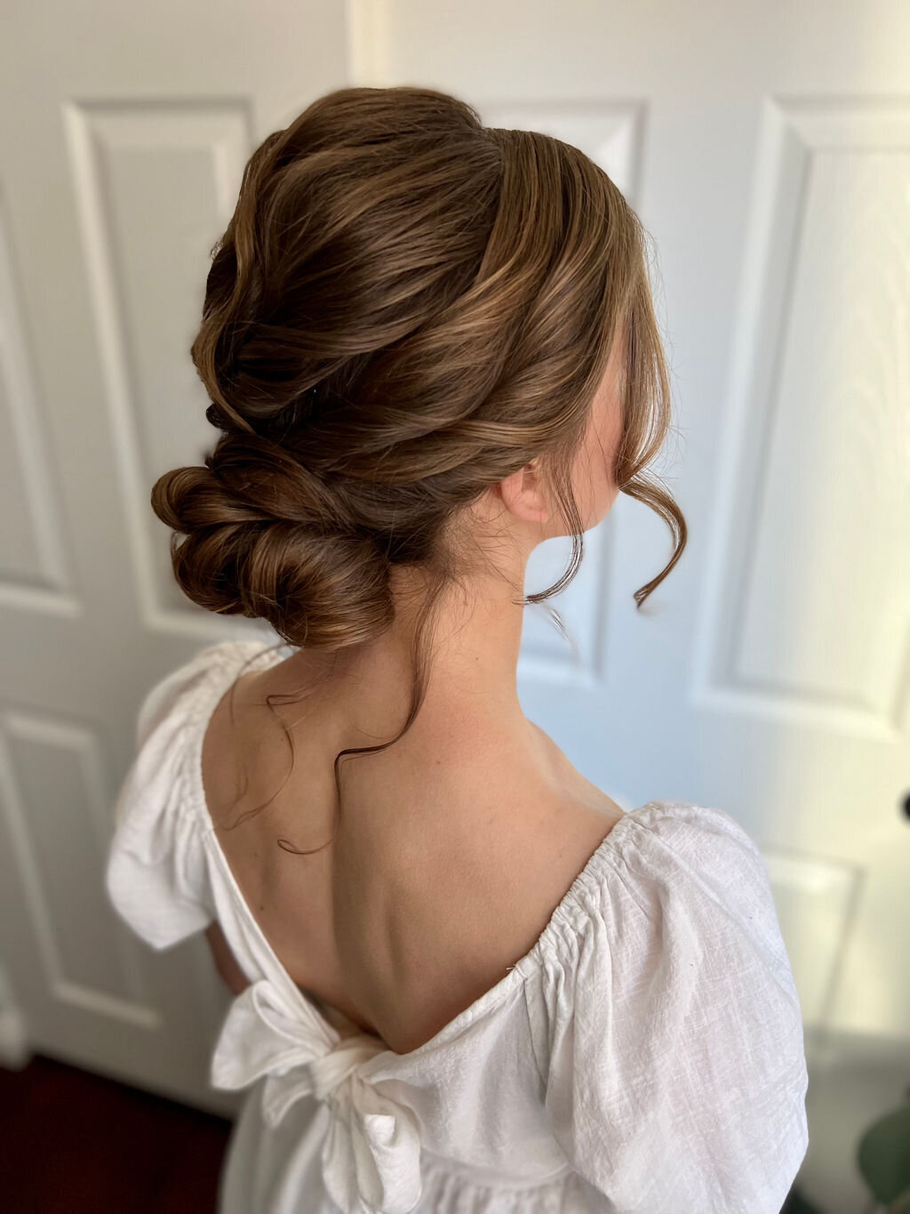Elegant low bun and glowing soft-glam makeup on a modern bride styled by Yana’s Beauty Studio for a San Francisco wedding.