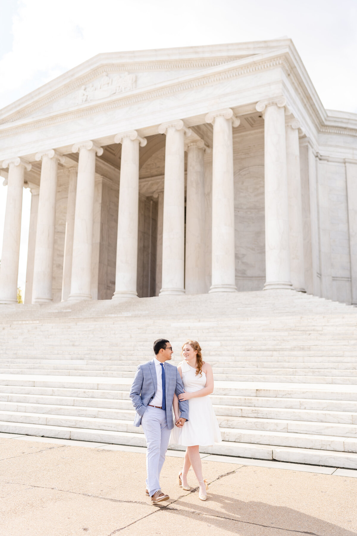 Boy and girl walking in front of Lincoln Memorial  while looking each other in DC for their engagement photos