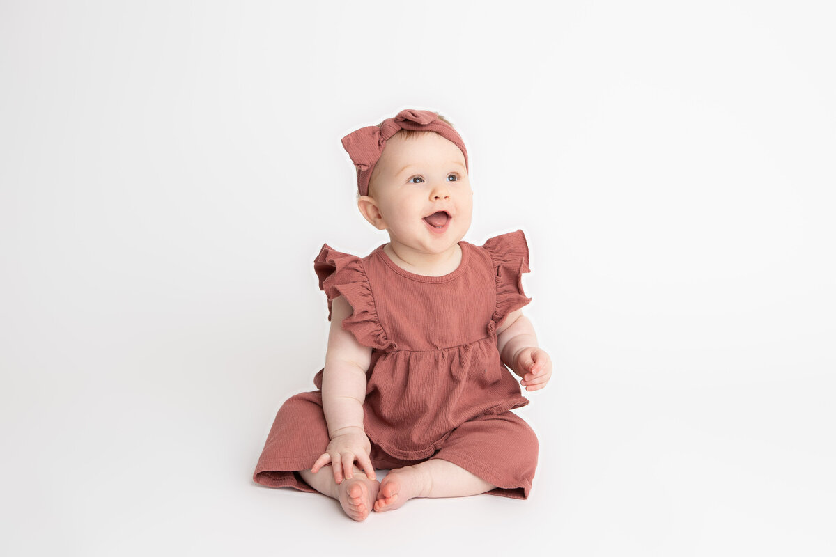 Baby girl in pink on a white backdrop