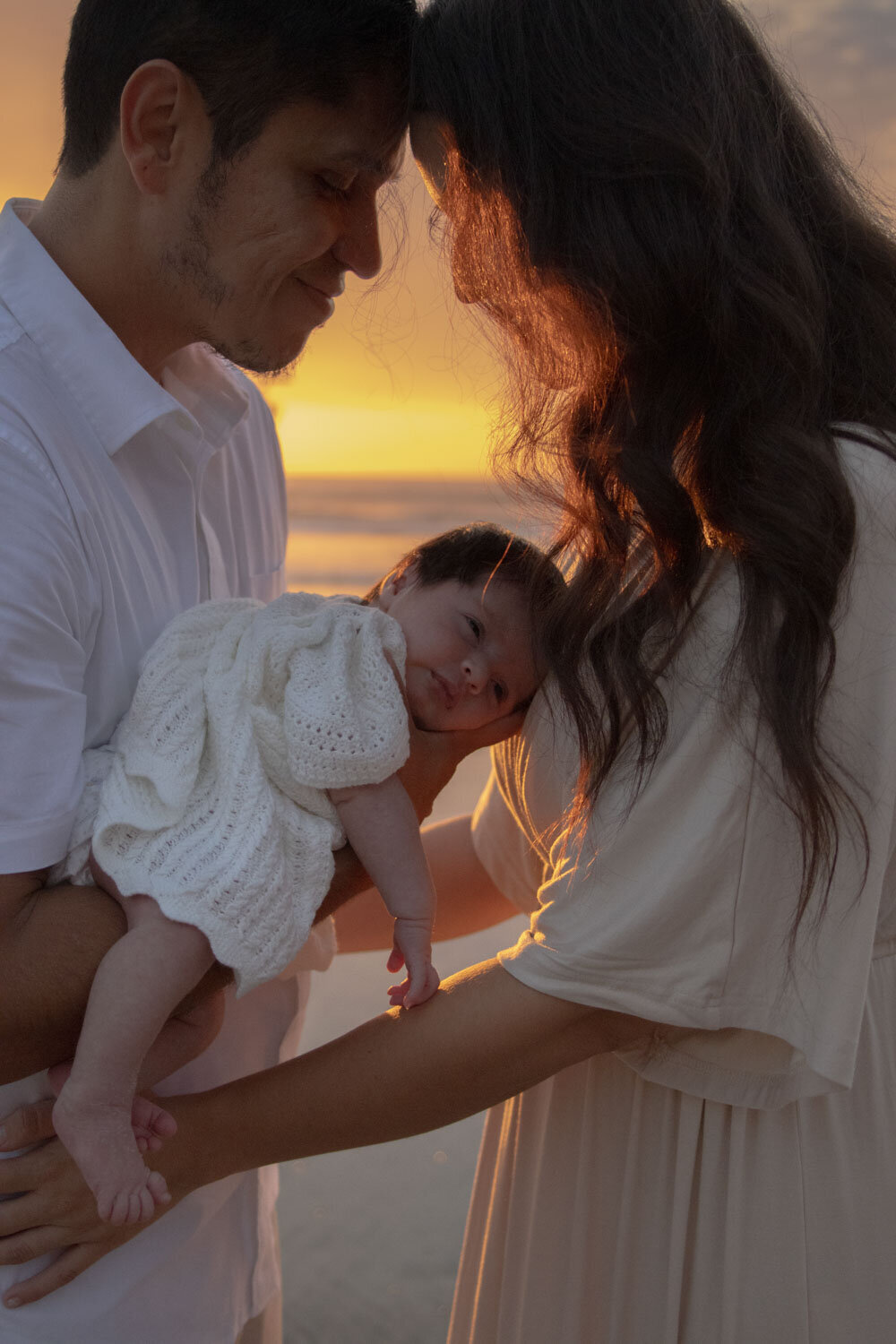 Parents sharing a tender moment with their baby at sunset