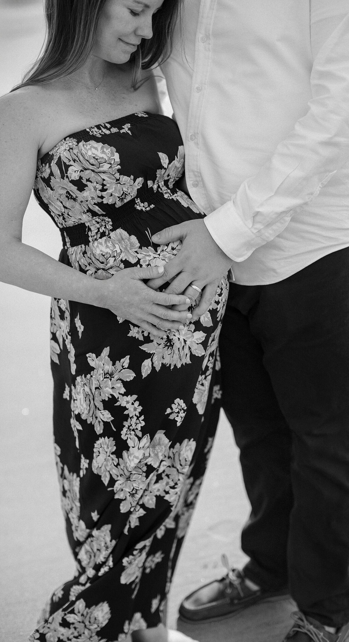 couple place hands on pregnant women's  belly.