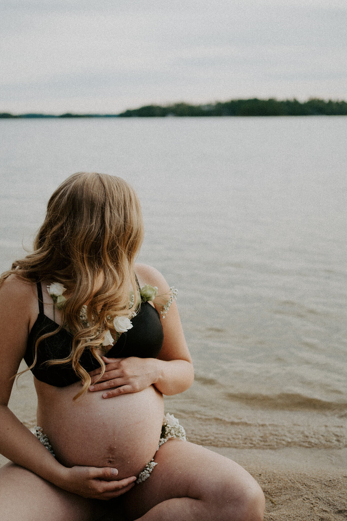 pregnant woman holding belly on beach