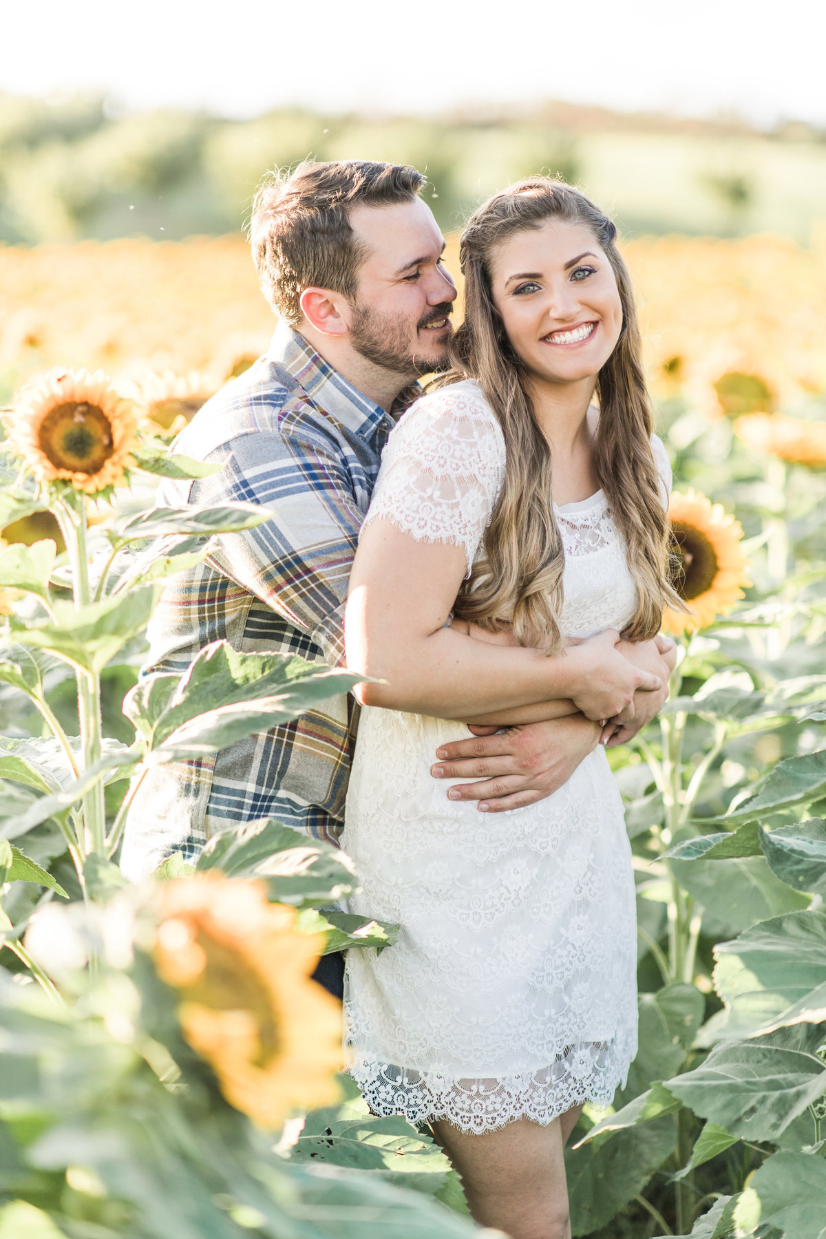 Couple embraces in a sunflower field.