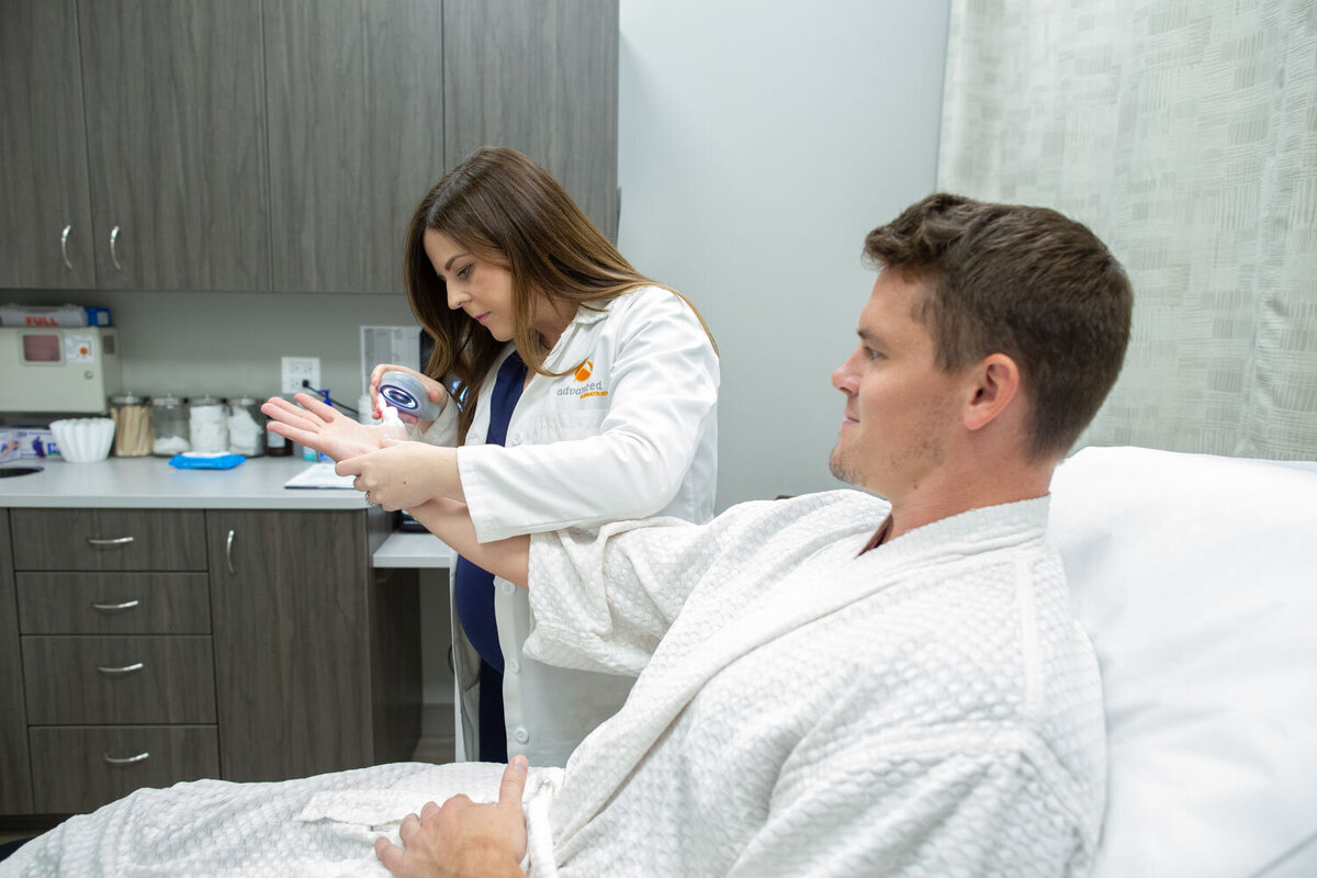 A woman in a lab coat is talking to a man in a hospital bed