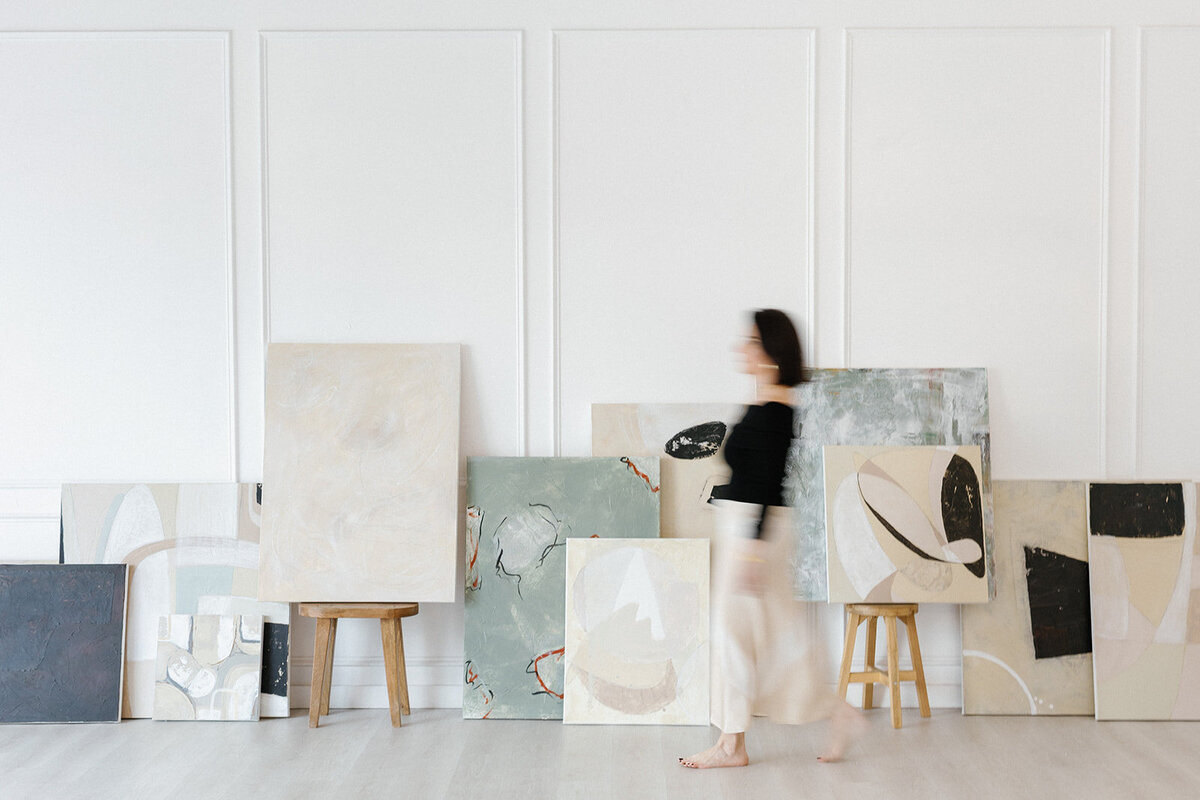 Branding photo of Dallas artist holding paintbrush in bright studio.
