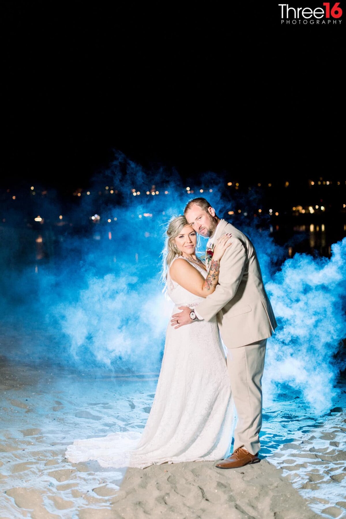 Bride and Groom cozy up with cheek to cheek during an evening photo shoot with a blue mist behind them