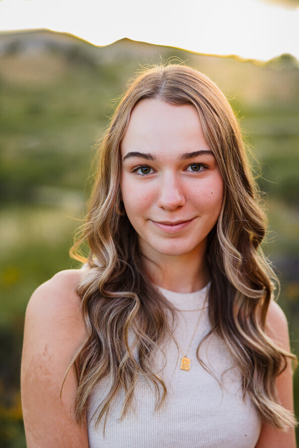 Girl with soft smile and long hair looks into camera.