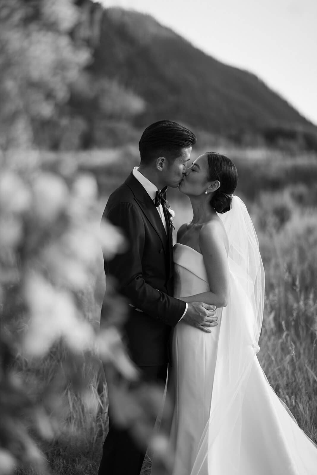 Bride and Groom share a kiss among Colorado outdoor greenery at their Aspen Meadows Resort wedding venue.