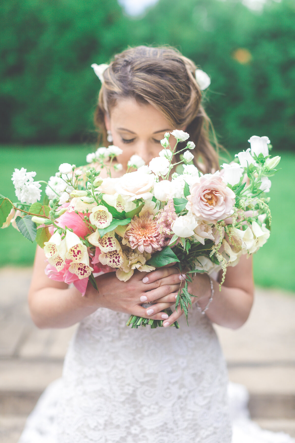 A bride smells a bouquet of lush flowers at a Montreal park wedding.