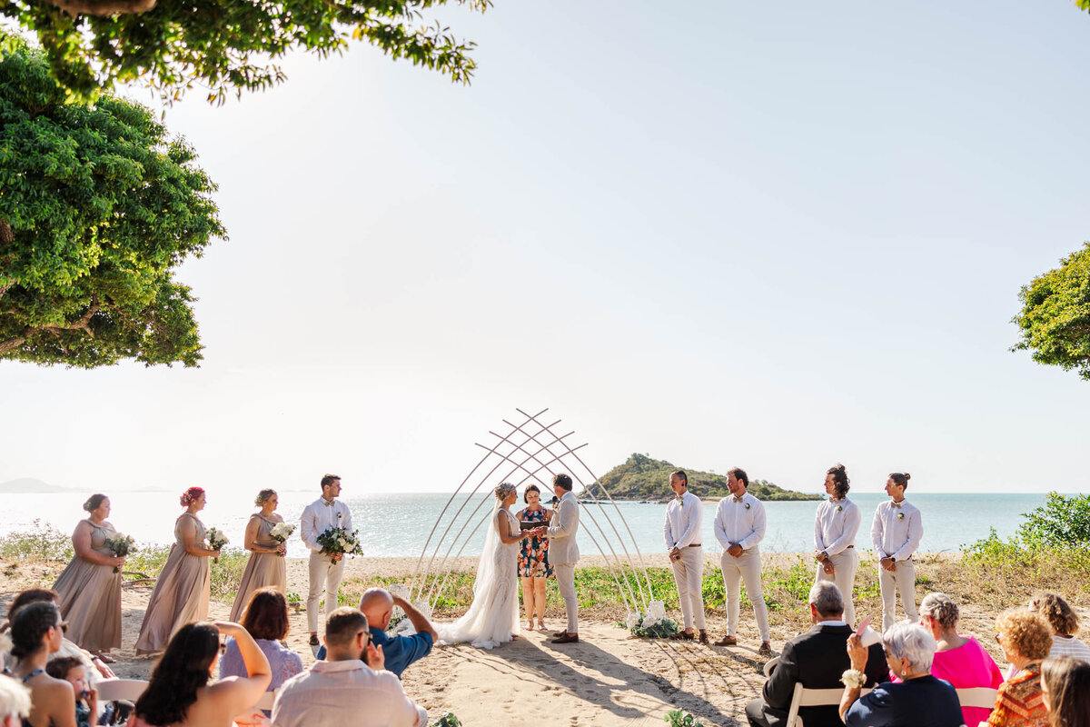 Bride and groom stand at their altar, saying vows to one another in front of the beautiful whitsunday, Cape Gloucester