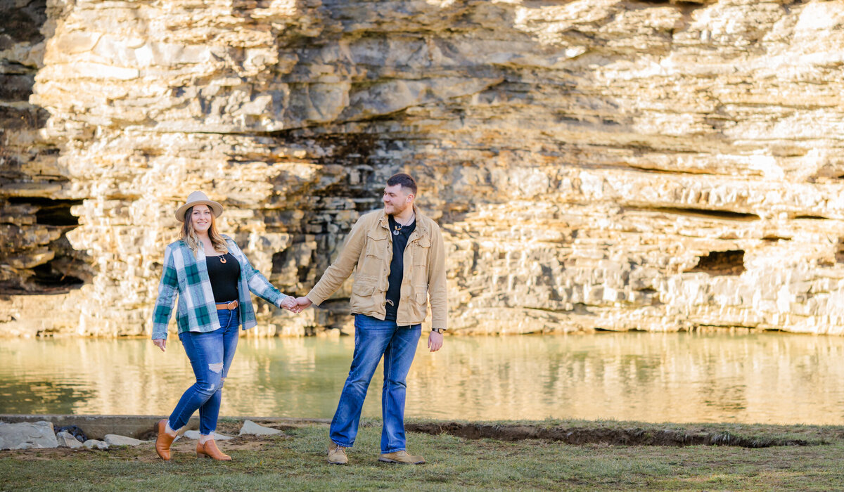 engaged couple walking at edge or water while holding hands at fall creek falls state park