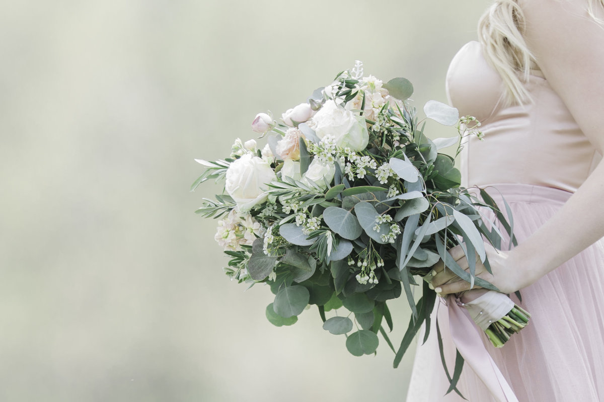 Midwest bride  holding flower bouquet on a blush wedding dress