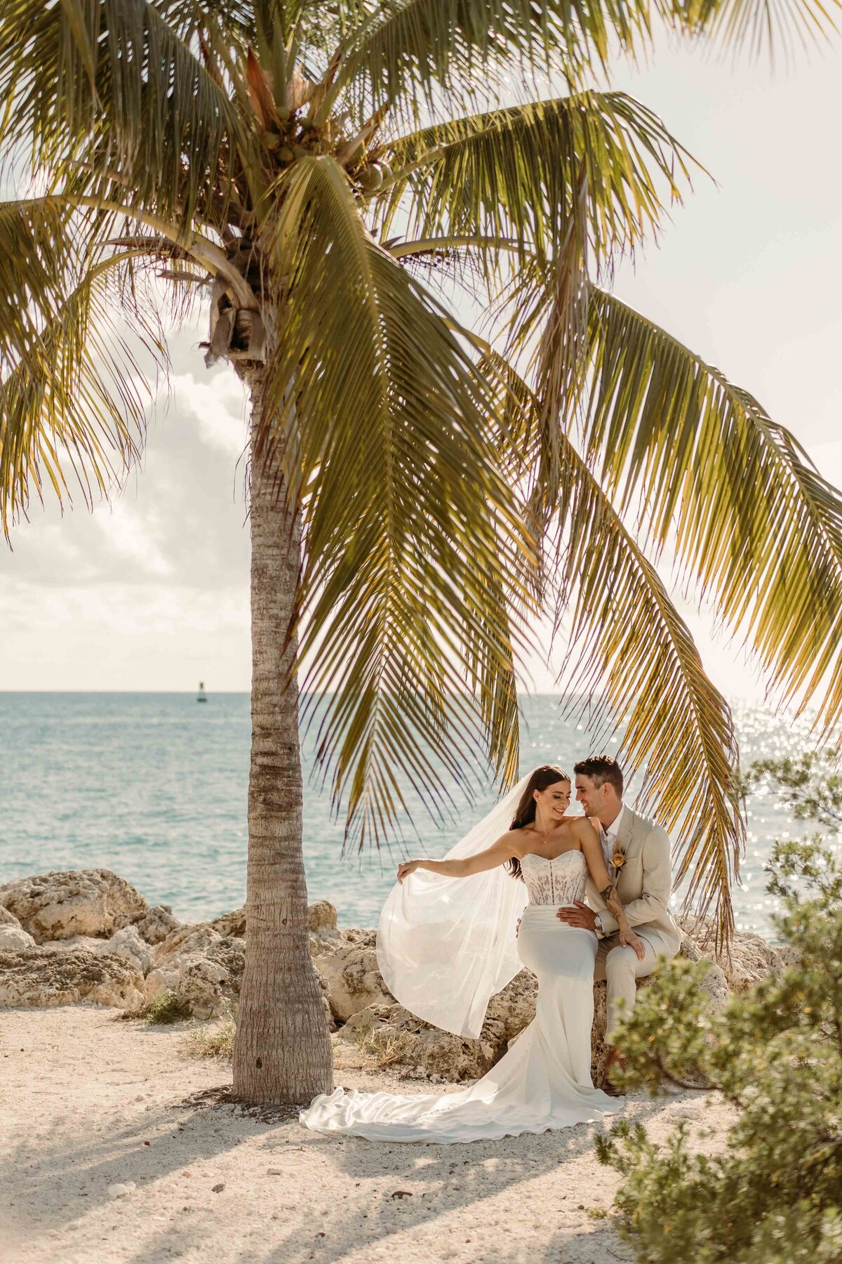 A bride and groom pose on the beach for photos  in Key West, Florida