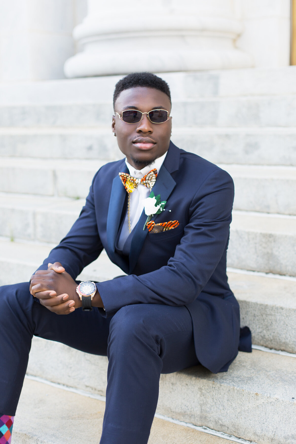 Young black teen sitting casually on stairs in front of the Federal Building  in Birmingham, AL for his prom pictures.