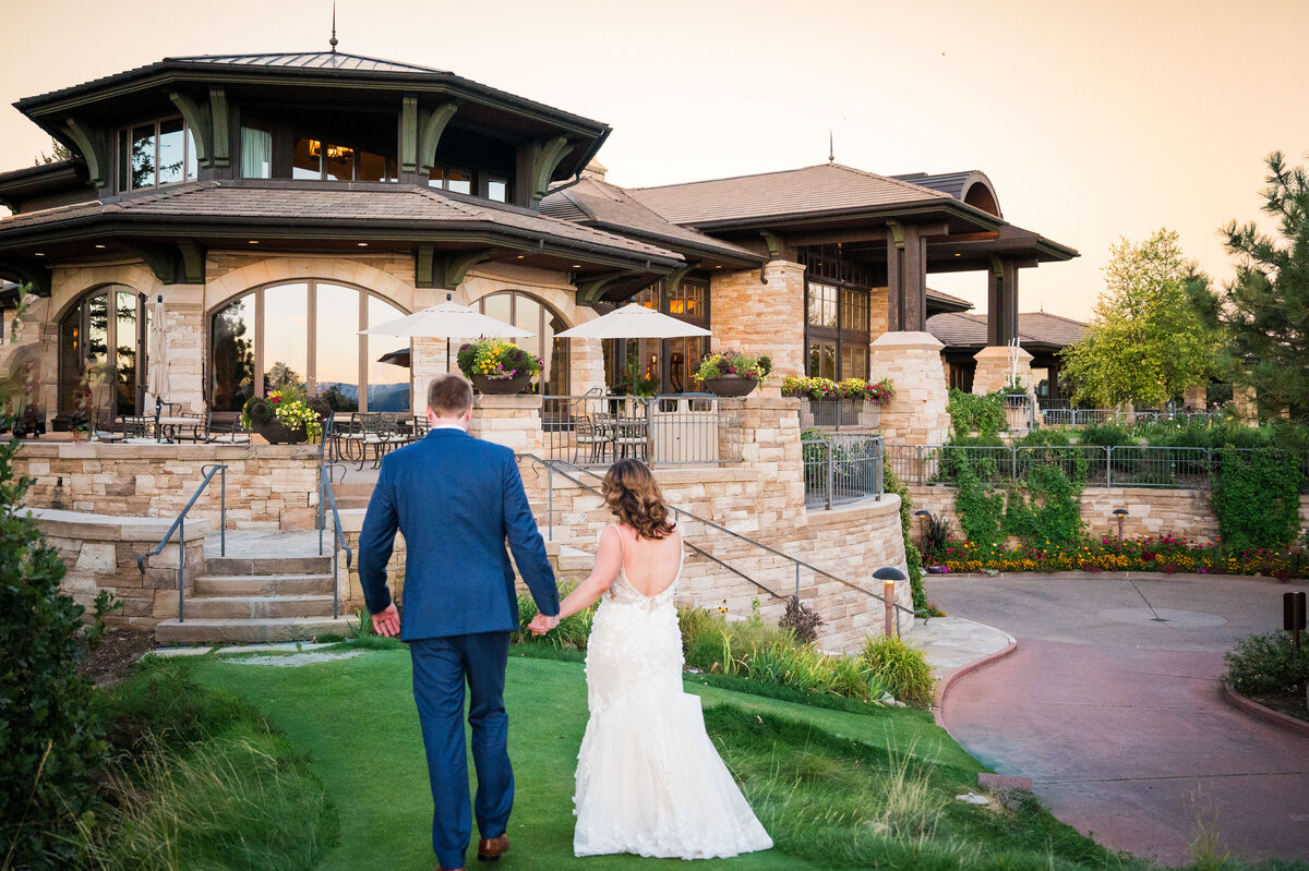 A bride and groom walk hand-in-hand toward their wedding venue, The Sanctuary in Colorado.