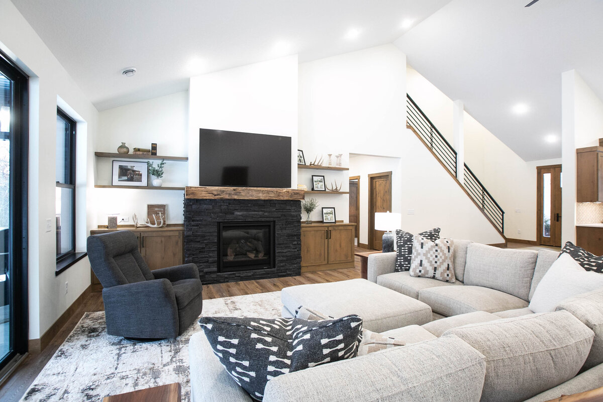 Cozy living room in Elk River custom home with fireplace, built-ins, and large windows