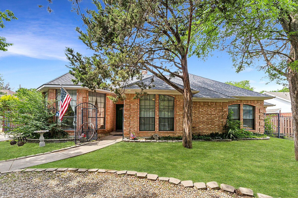 Front exterior of 6419 Shadow Lane in Dallas, Texas — a single-story brick home with gated entry, mature trees, and charming curb appeal, listed by Haven Realty Group.