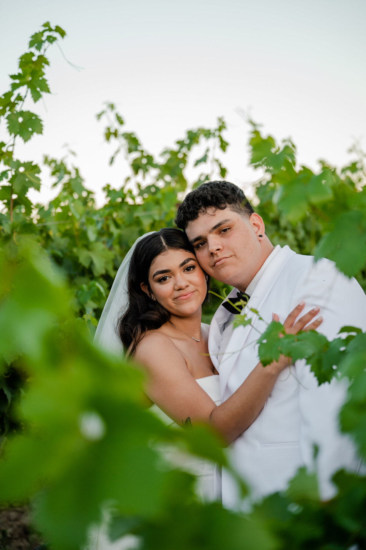 Bride and groom walking through the vineyards at Toca Madera Winery, surrounded by lush greenery.