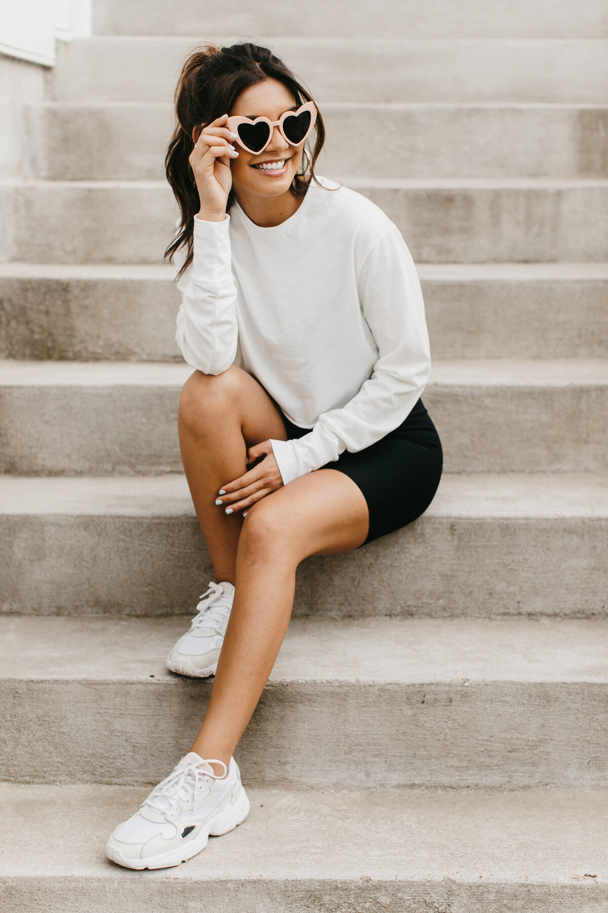 model sitting on stairs in sweatshirt and heart shaped sunglasses