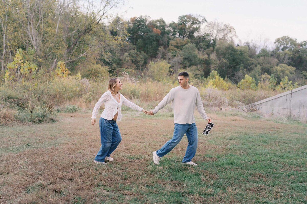 pregnant mom and dad hold hands at seven islands state birding park in october in kodak tennessee