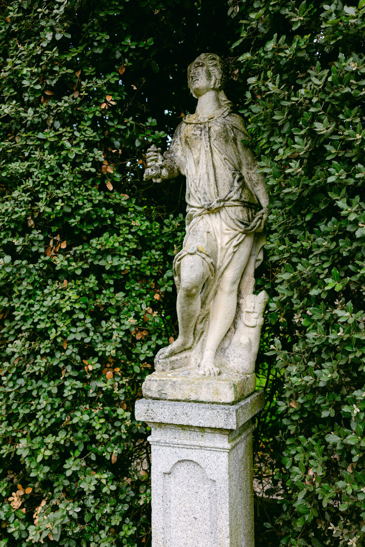 A wedding day photo of a statue in the gardens of the wedding venue villa balbiano on Lake Como in Italy