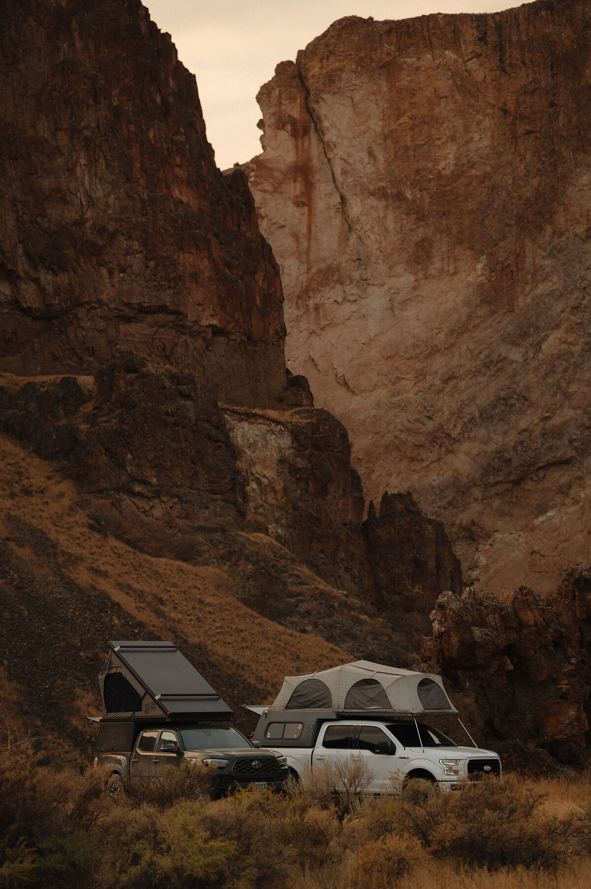 trucks with pop up campers park next to towering rocks in Moab, Utah