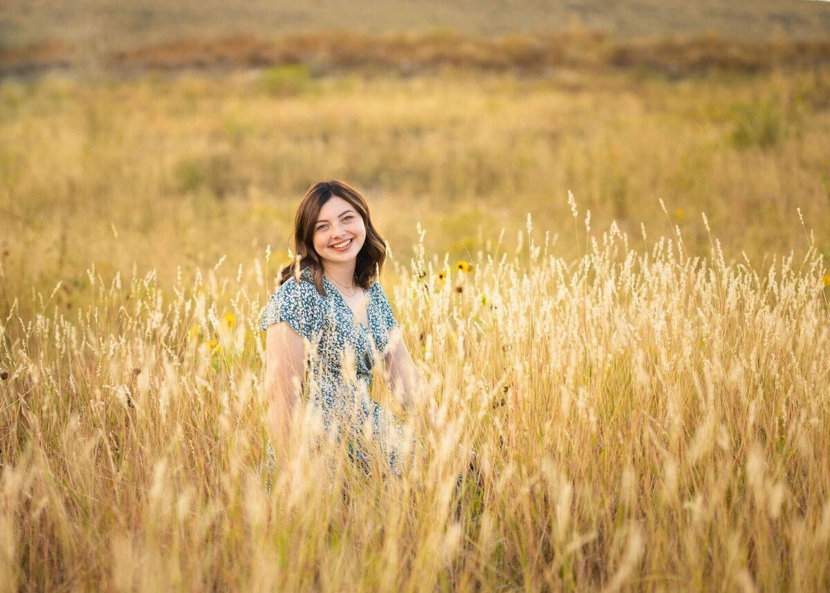 high school senior girl sitting in a tall grassy field