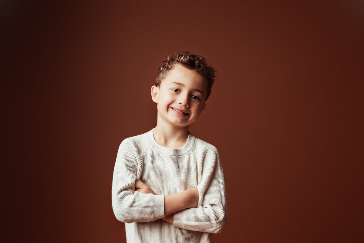 boy-crossed-arms-brown-studio-backdrop