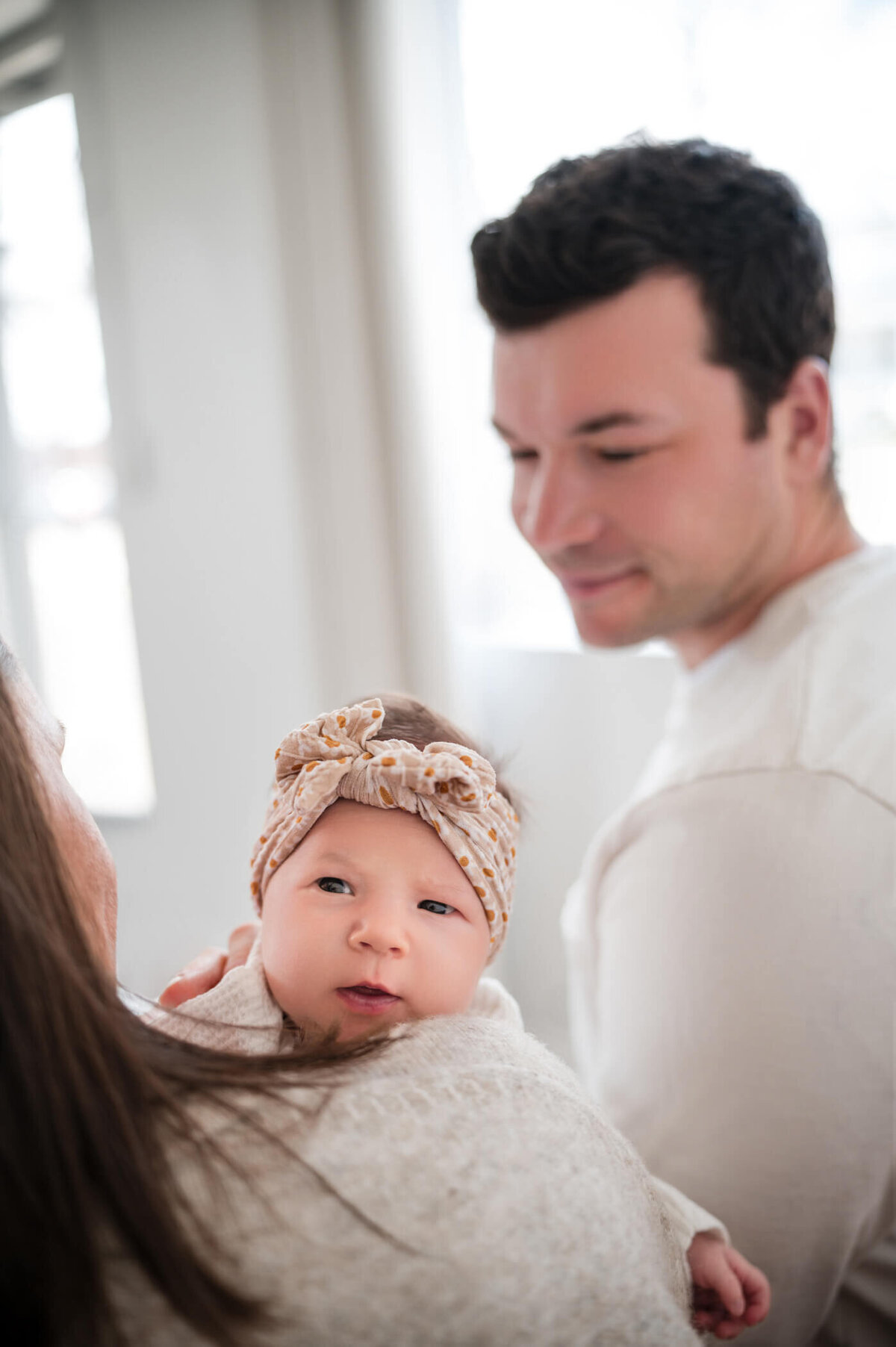 newborn looking at camera over mom's shoulder