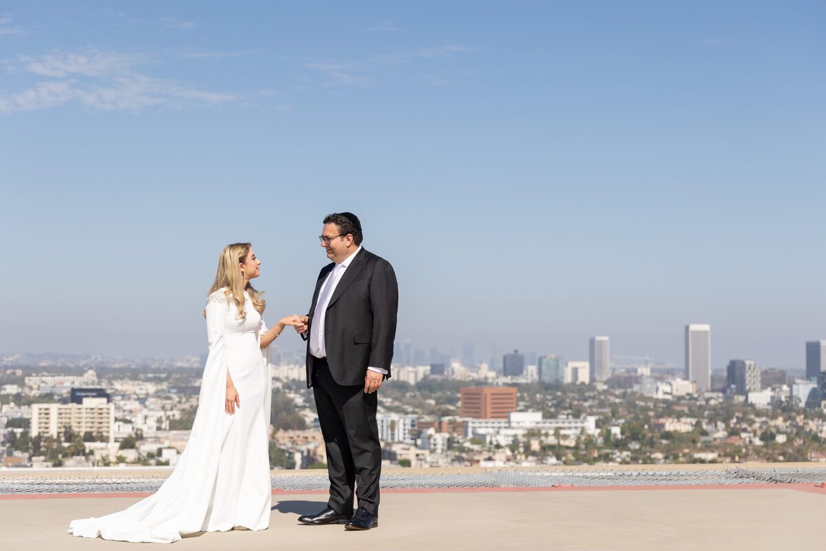 A newlywed couple holding hands on the top of a roof