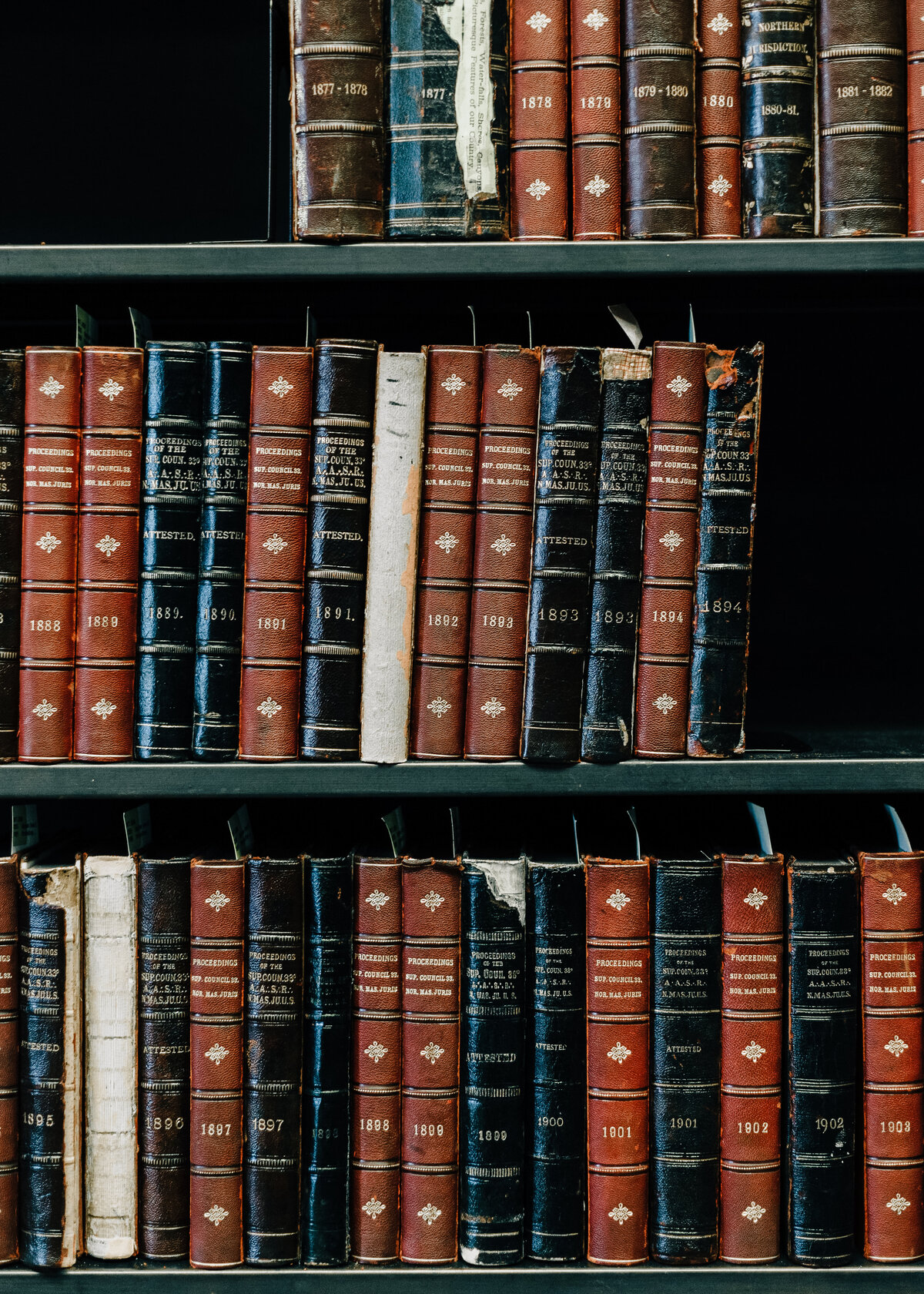 A bookshelf is stacked with vintage leather bound books. Interior design.