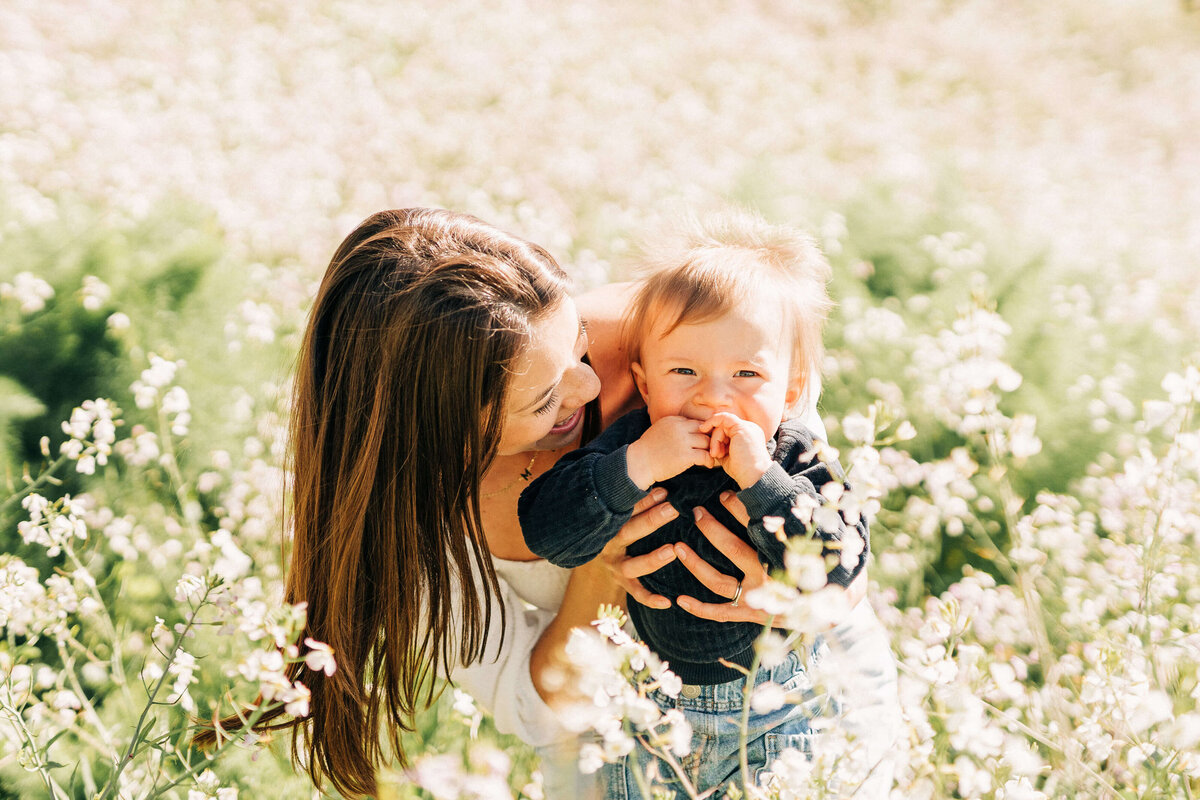 mother and son smiling at the camera during motherhood session at a wildflower field