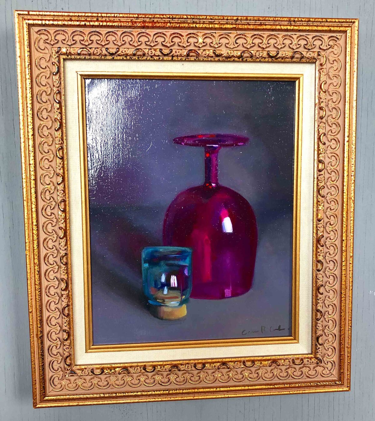 Still life oil painting of large pink glass goblet set upside down and small blue glass cup