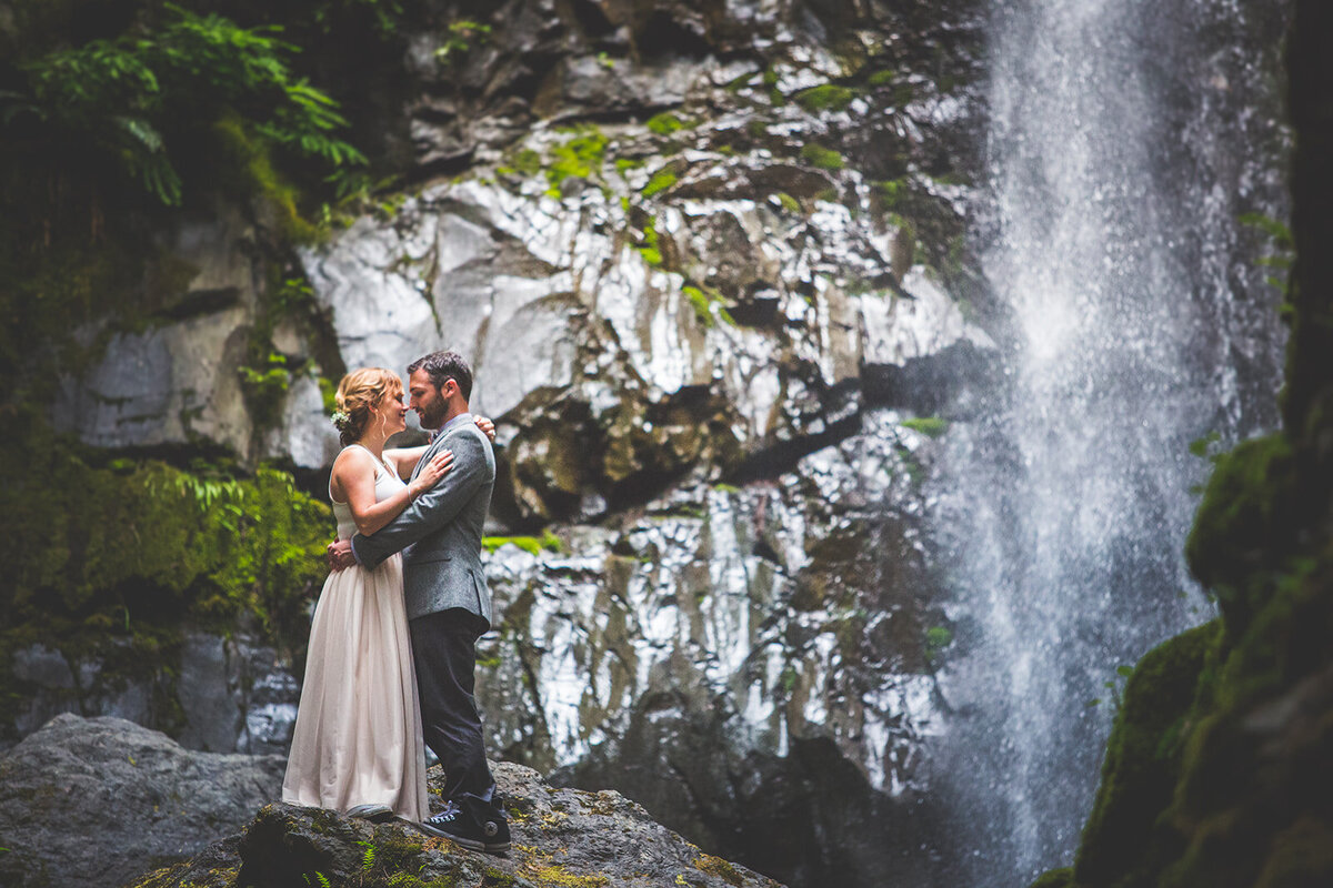 A couple hugging by a waterfall on their wedding day on Vancouver Island.