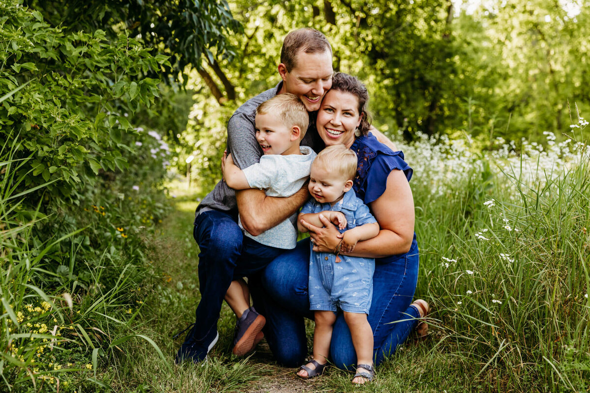 two toddler boys hugging their parents as  the father looks at the mother for their family photo session