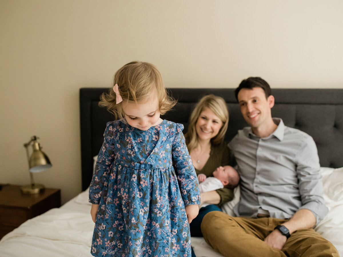 family sitting on bed for newborn in home lifestyle photography session cleveland newborn photographer