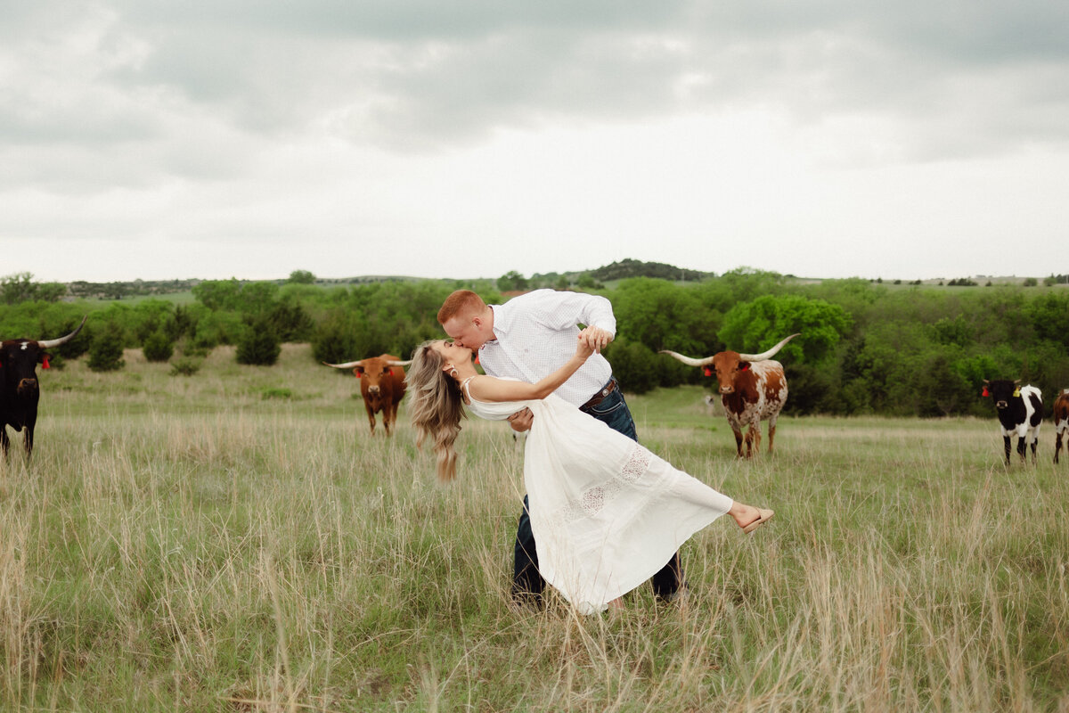 country wedding photo ideas| bride and groom dancing through a field with bulls in the background.
